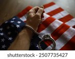 Hand in Handcuff on American Flag Symbolizing Law Enforcement and Justice in the USA