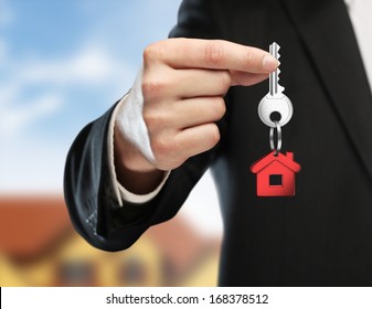 Hand Handing Key On Cottage Background