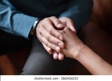 Hand in hands. Close up of young man husband boyfriend holding hand of beloved mixed race woman wife girlfriend comforting supporting in grief, asking forgiveness, apologizing after family argument - Powered by Shutterstock