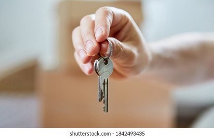 Hand hands over key of property symbolizing home ownership and buying a house