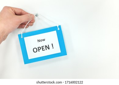 Hand Hanging Now Open Signage On White Door Background. Business Opening Concept.