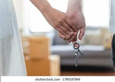 Hand Of Happy Young Couple Man And Woman Handing Their New Home Keys In Front Of An Open House Door