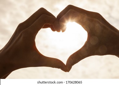 Hand Heart Shape Silhouette Made Against The Sun & Sky Of A Sunrise Or Sunset