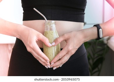 Hand In Heart Symbol Holding Smoothie Drink Detox On Fit And Slim Belly Woman. Fitness Wellbeing Concept. Body Care, Clean Eating, Weight Loss Diet Concept. Woman With Bowel Or Reproductive Problem.