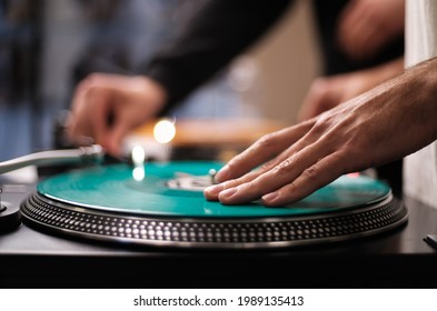 Hand of hip hop dj scratching vinyl record on turntables. Professional disc jockey scratches records on party in night club on analog turn table player device. Djs setup on stage