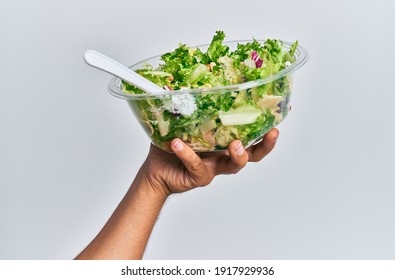 Hand of hispanic man holding bowl with salad over isolated white background.
