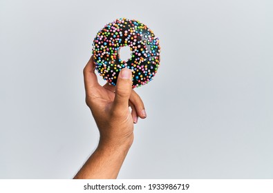 Hand Of Hispanic Man Holding Chocolate Donut Over Isolated White Background.