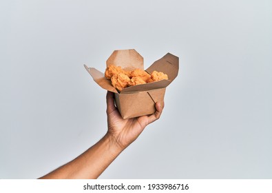 Hand Of Hispanic Man Holding Fried Chicken Over Isolated White Background.