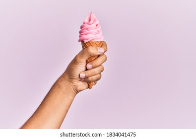 Hand Of Hispanic Man Holding Ice Cream Over Isolated Pink Background.