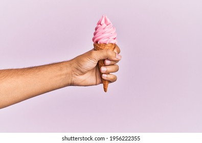 Hand Of Hispanic Man Holding Ice Cream Over Isolated Pink Background.