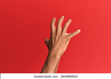 Hand Of Hispanic Man Over Red Isolated Background Grasping Aggressive And Scary With Fingers, Violence And Frustration 