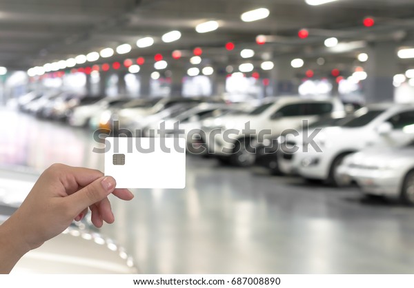 hand hold\
blank card on blurred car parking with bokeh light Background. use\
for advertise about promotion credit\
card