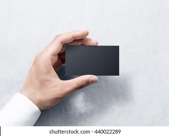 Hand hold blank plain black business card design mockup. Clear calling card mock up template holding arm. Visit pasteboard paper surface display front. Check small offset card print. Business branding