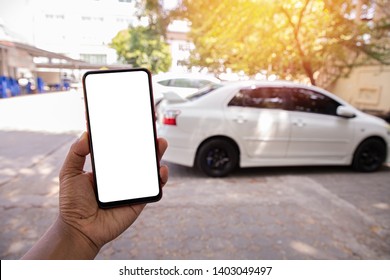 Hand Hold Blank Screen On Mobile, Cellphone, Tablet On Blurry White Car. Concept Of Find Used Card Online.