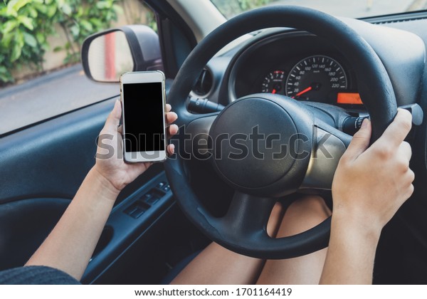 Hand hold blank
screen smartphone inside car at driver seat, surfing internet or
making phone call inside
car