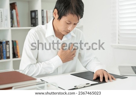 hand hold chest with heart attack symptoms, asian man working hard have chest pain caused by heart disease, leak, dilatation, enlarged coronary heart, press on the chest with a painful expression