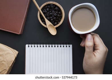 hand hold coffee cup and blank notebook on black bankgrounds - Powered by Shutterstock