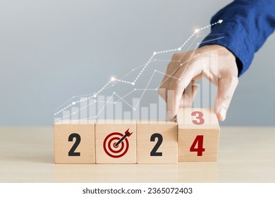 Hand hold coin with coins stacks and up arrow with the number 2024. Concept of interest rate,investment and dividend - Shutterstock ID 2365072403