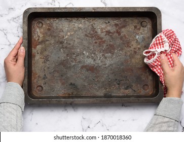 hand hold empty metal rectangular baking sheet on a white table, top view
