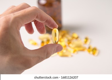 Hand Hold Fish Oil Capsule With Fish Oil Background.