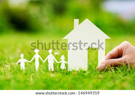 Hand hold house against green field