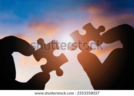 Hand hold jigsaw puzzle with silhouette sunlight effect sky clouds.
Strategies for business success. 
Collaboration and teamwork concept.