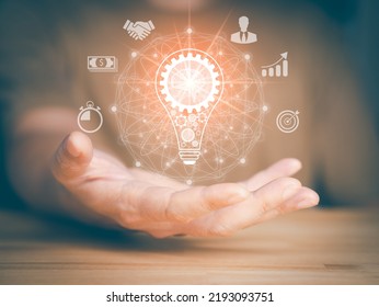 Hand hold light bulb, gears icon and brain inside the light bulb. Money, connection, chart, target sign, times and people icon. Idea of ​​inspiration online technology and innovation idea concept. - Shutterstock ID 2193093751