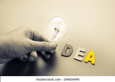 Hand hold light bulb as symbol of Idea word