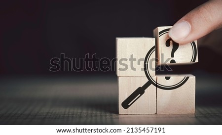  Hand hold magnifying glass and question mark sign icon in wooden cube. Problems and root cause analysis concept. copy space for background or text.