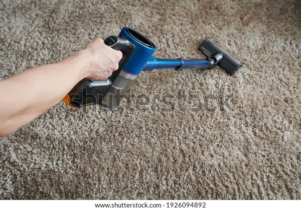 Hand hold\
modern vacuum cleaner on carpet\
background