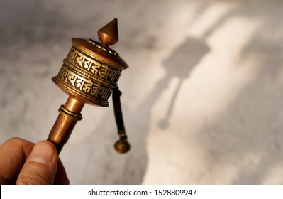 Hand hold old Tibetan prayer wheel with shade in the morining ,Buhhist prayer concept ,selective focus