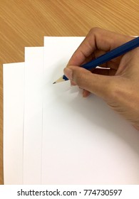 Hand hold pencil writing on white paper on table wood background ,three papers art for draw plan thinking of business education student artist