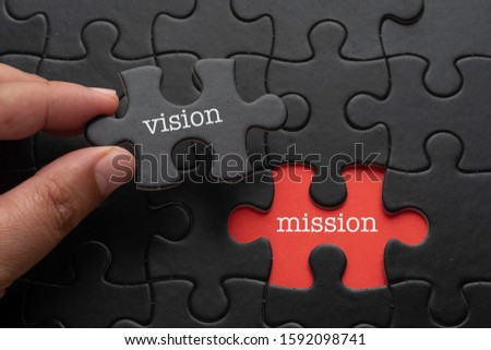 Hand hold piece of puzzle written VISION revealing word MISSION. Business concept.