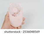 a hand hold  pink Mini electric fan, Small fan for traveler background.