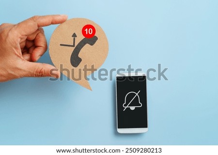 hand hold real brown speech bubble paper cut with missed call symbol  and white mobile phone with do not disturbed sign on blue background