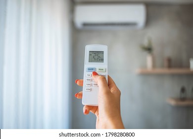 Hand hold remote control directed on the air conditioner. Woman hand using remote control open air conditioning 25 degrees. Open air 25 degrees, is temperature, save energy - Shutterstock ID 1798280800