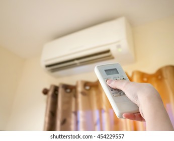 Hand hold remote control directed on the air conditioner - Shutterstock ID 454229557