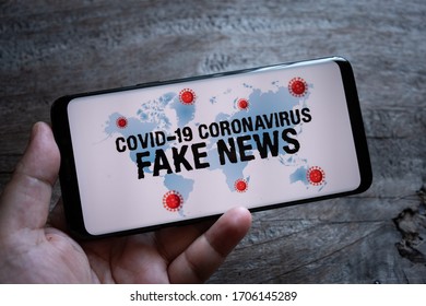 Hand Hold Smartphone With Covid-19 Coronavirus Fake News. 