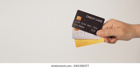 La mano tiene tres tarjetas de crédito. Tarjetas de crédito de color oro y plata negro aisladas en fondo blanco.
