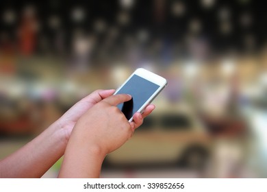 hand hold and touch screen smart phone, on blurred image of motor show,show room,motor expo for background