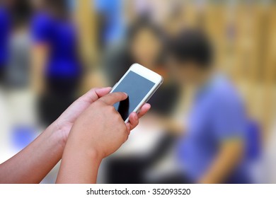 hand hold and touch screen smart phone, on abstract Businessmen and women blur in  work conference