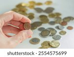 Hand holding a 1 euro cent coin in front of many coins in the background