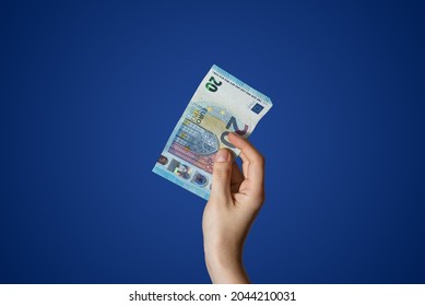  Hand holding a 20 Euro bill isolated on blue background. High quality photo