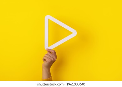 Hand Holding 3d Media Play Button Over Yellow Background