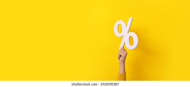 hand holding 3D  percentage symbol over yellow background, panoramic image - Shutterstock ID 1920290387