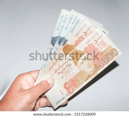 hand holding 5000 and 1000 Pakistani currency banknotes on white background. Pakistani currency banknotes