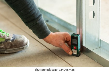 Hand Holding An Accurate Laser Meter On The Floor.