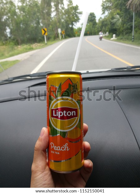 Hand holding
aluminium can of Lipton ice tea with peach on road background,
July, 2018, Chiang mai,
Thailand