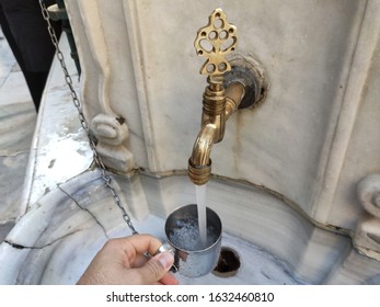 A Hand Holding Aluminum Cup Filling Water From Water Tap. People Can Drink Or Receive Water For Free.