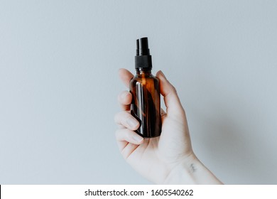 Hand holding an amber spray bottle